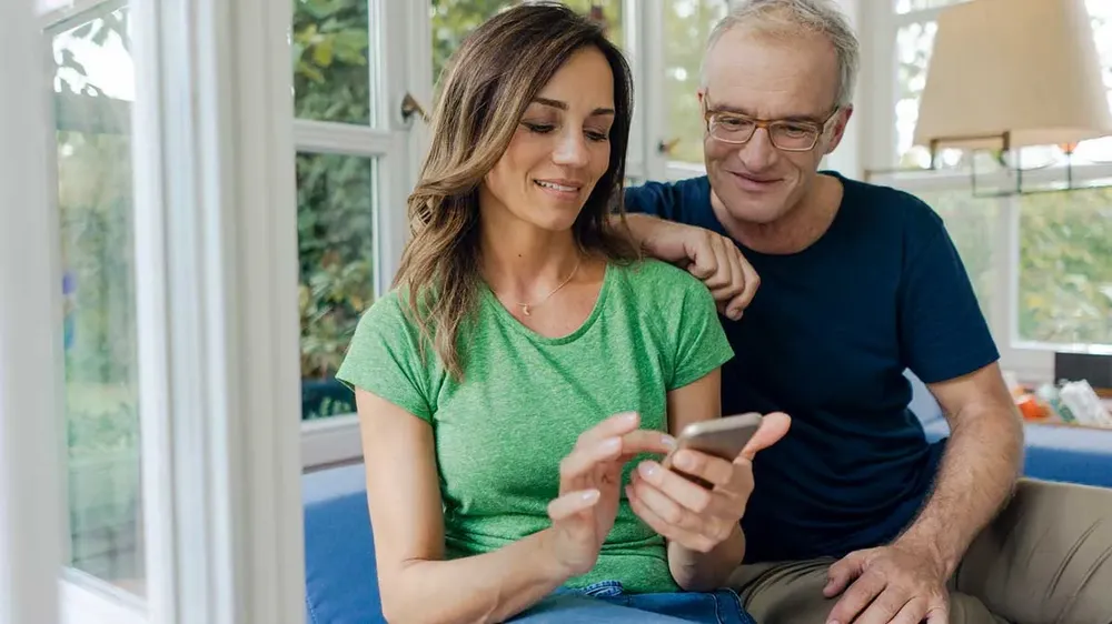 A couple of customers reading reviews on their phone at home before hiring